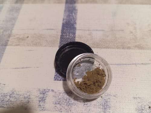 Vasetto di Dry Sift Slow Weed (resina dorata) su tovaglia blu e bianca