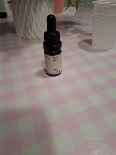 Bottiglia di Olio CBD 24% Slow Weed su tovaglia a quadretti rosa e bianchi
