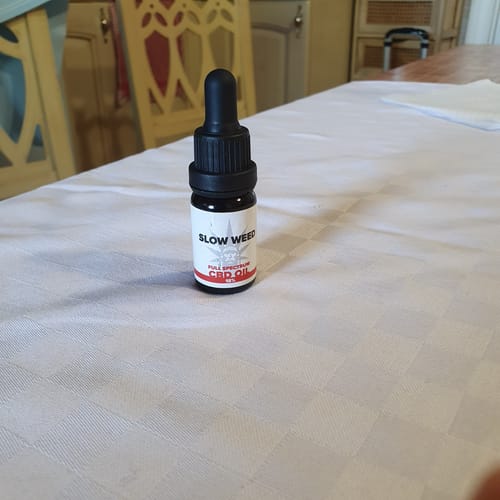 Bottiglia di Olio CBD Slow Weed su tavolo da pranzo con tovaglia color crema