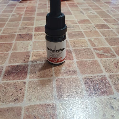 Olio CBD Slow Weed in primo piano su pavimento a piastrelle terracotta